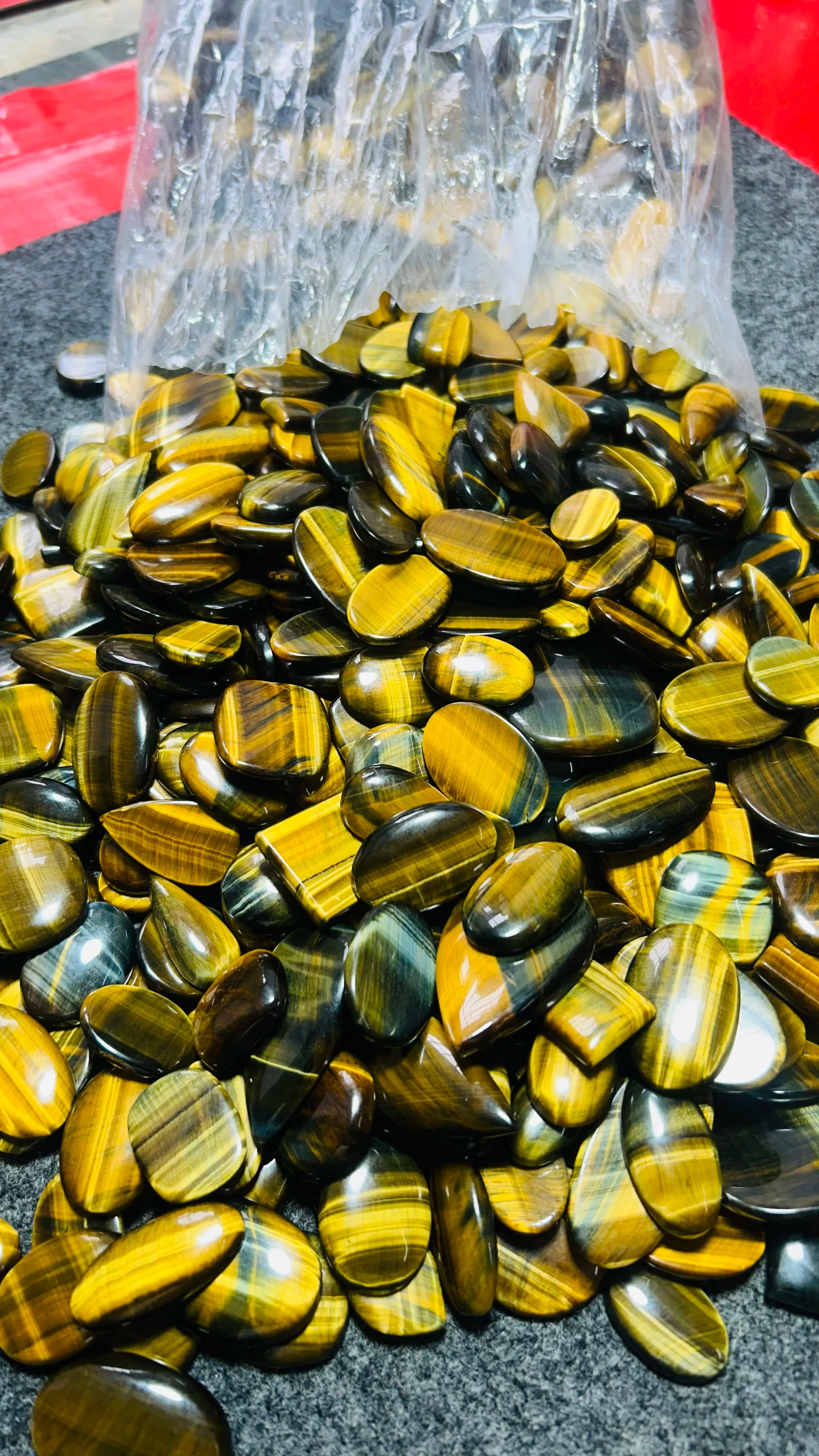 Loose striped cabochon gemstones in a clear bag, yellow-gold and dark tones