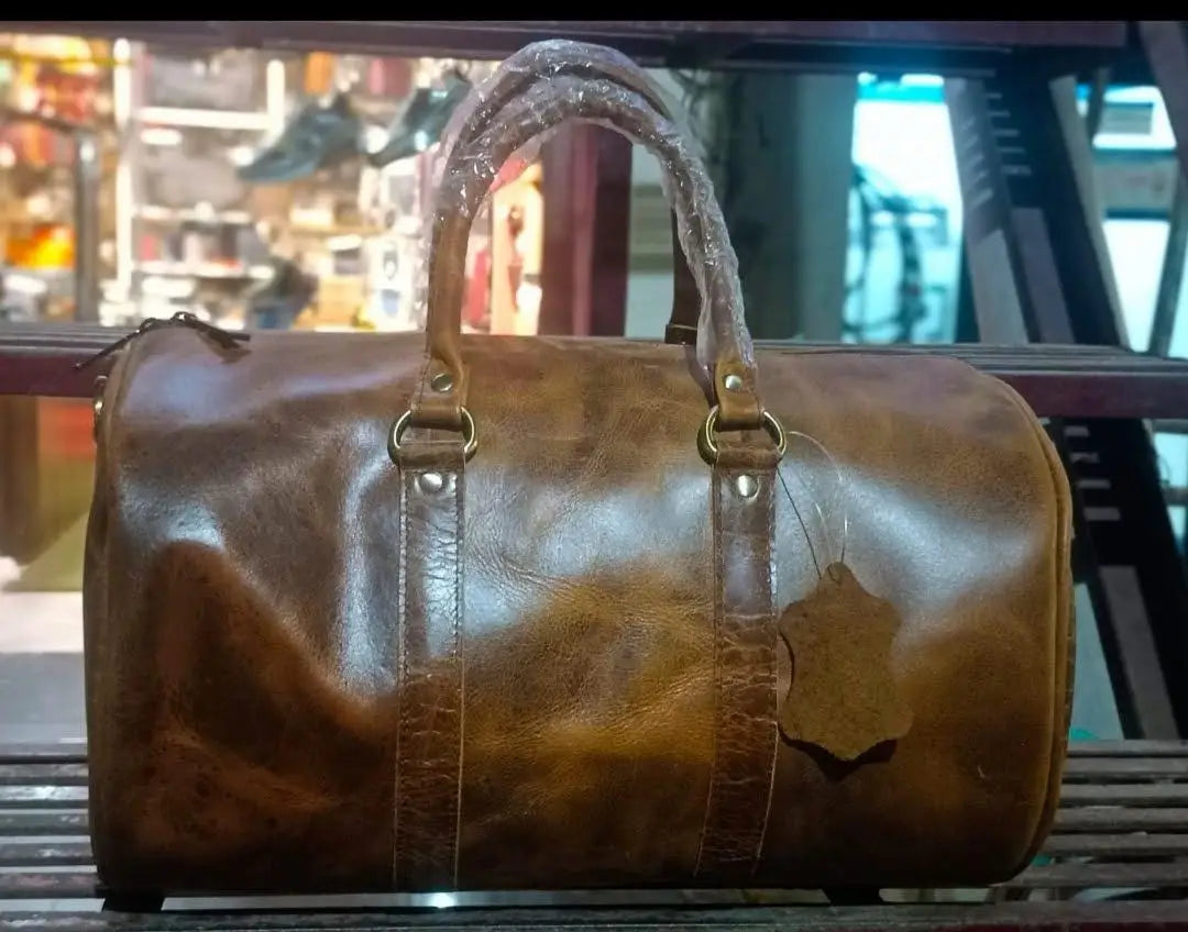 Large brown full-grain leather trunk duffel bag for sports and travel, featuring durable handles and luxury design.