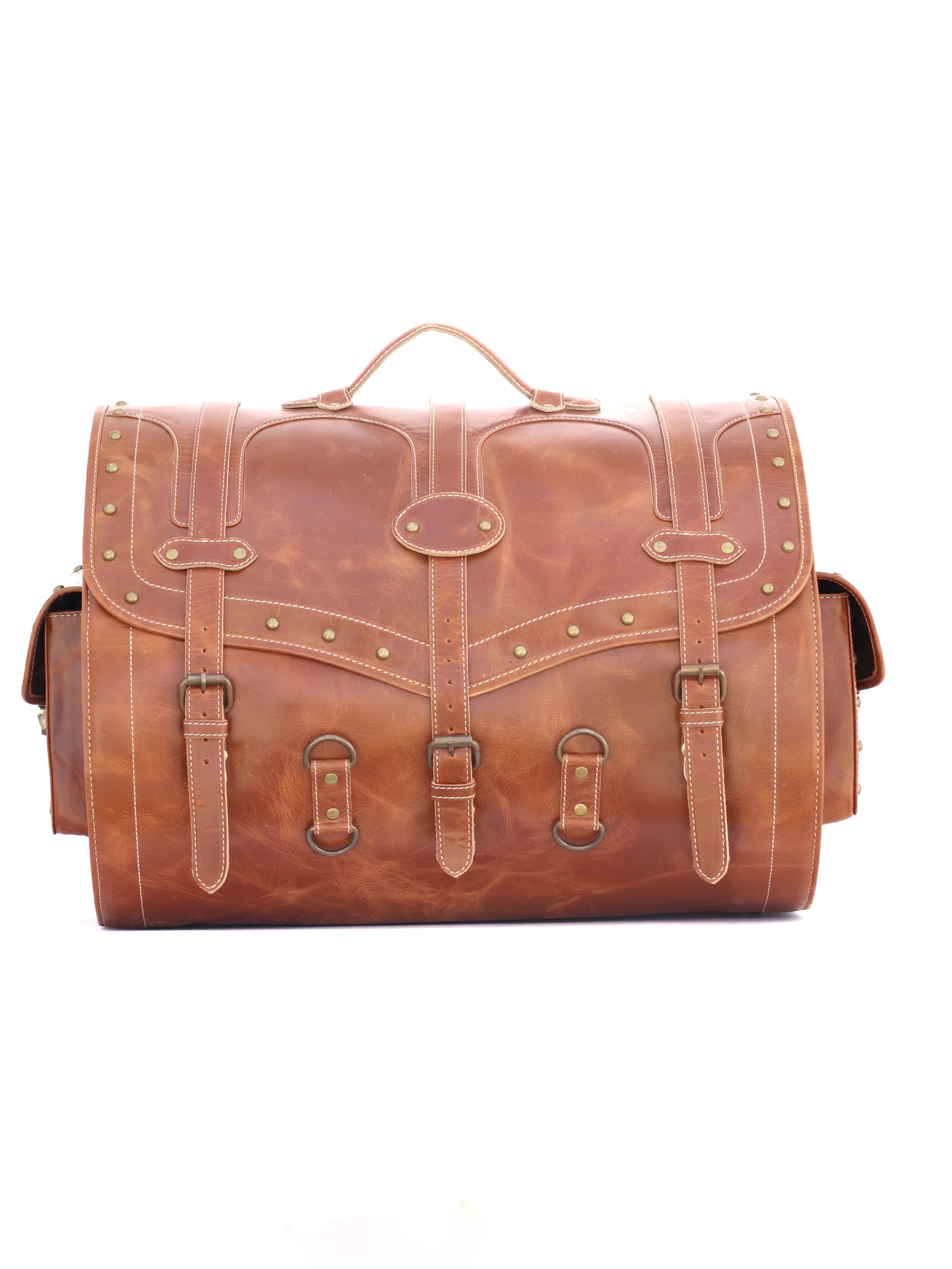RABADA brown leather trunk travel bag with vintage brass buckle straps, rivet detailing, and spacious luggage design.