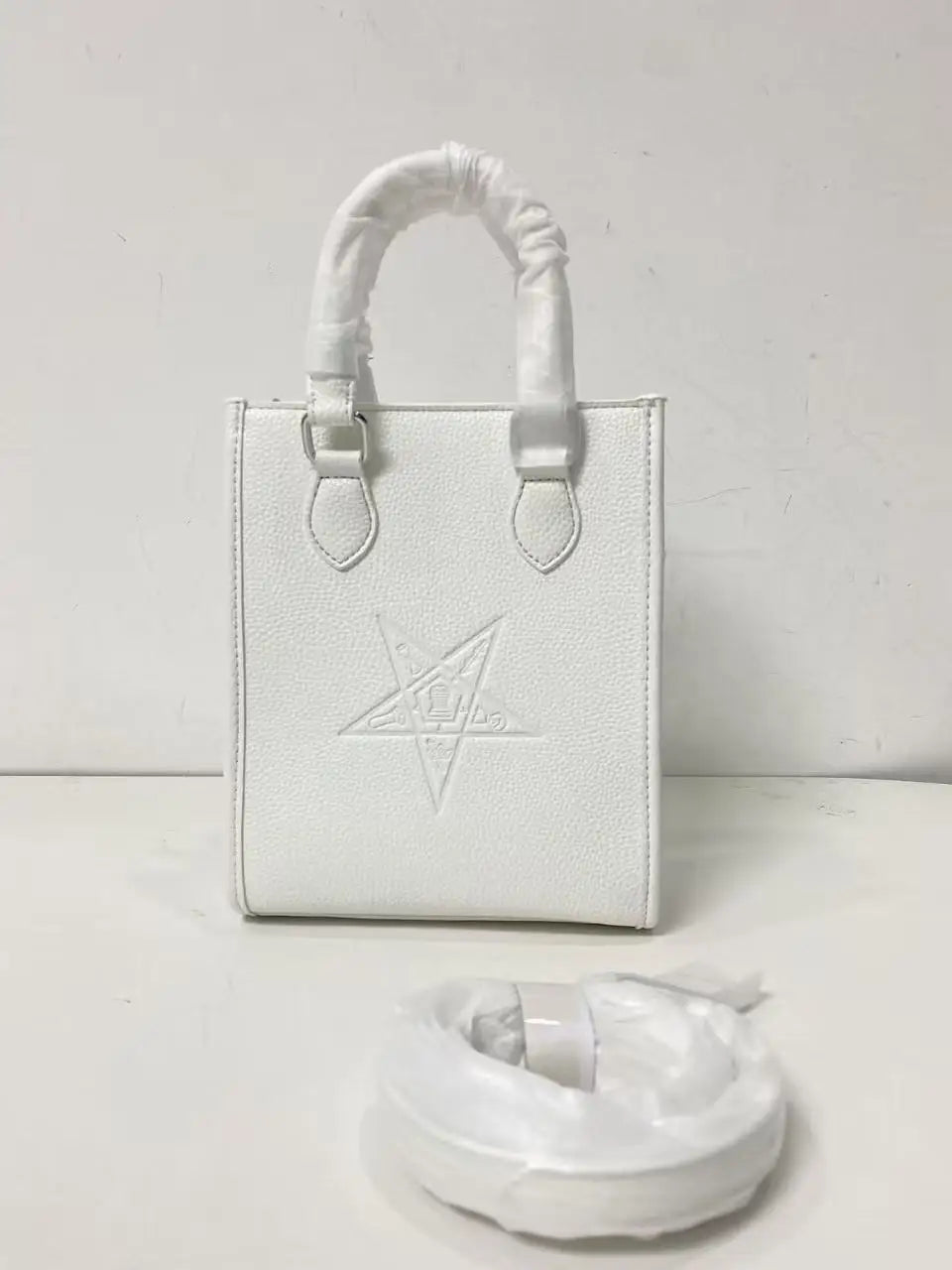 White genuine leather designer crossbody bag with embossed Order of the Eastern Star emblem and protective wrapping.
