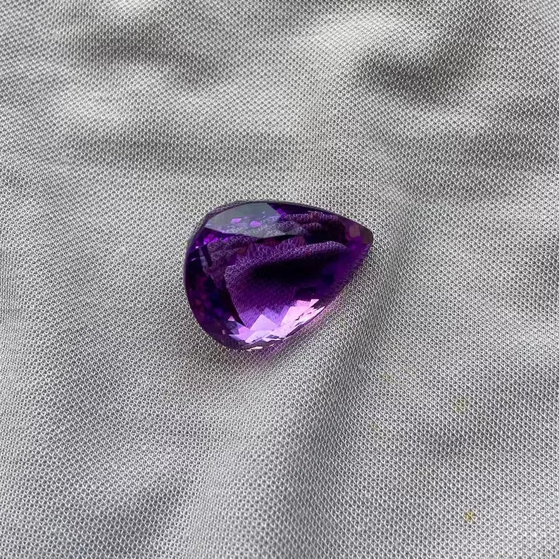 Amethyst pear cut gemstone with vivid purple coloring and bright faceted highlights