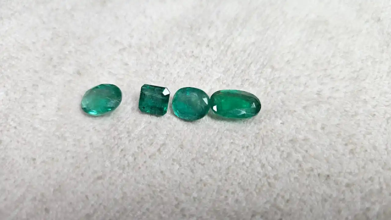 Loose green emerald-cut gemstone mix, five small stones on felt in a line