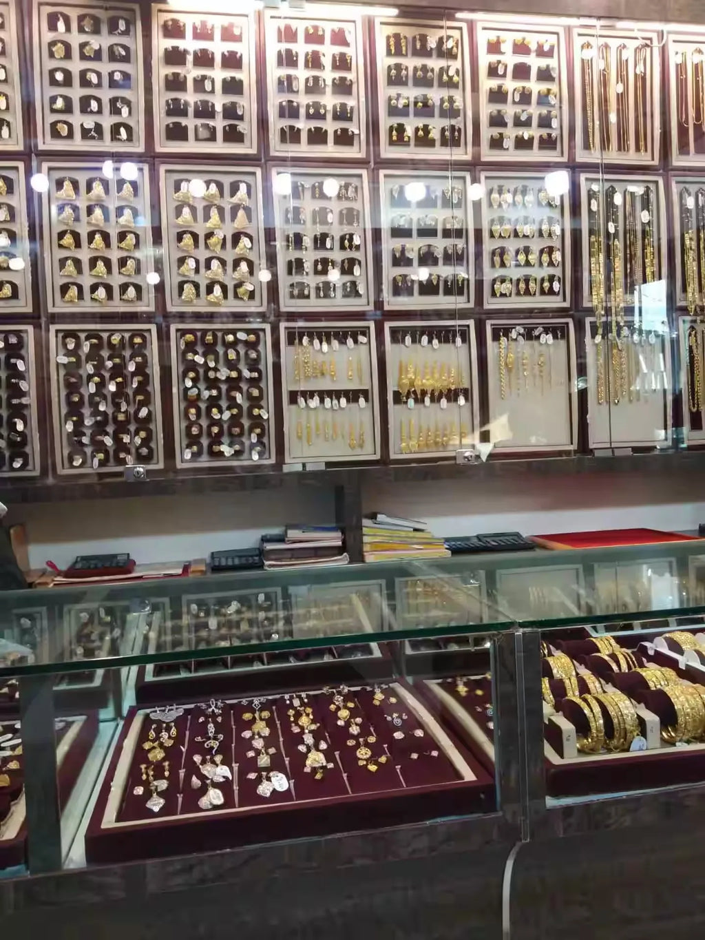 Jewelry store display wall with rows of earrings and necklaces in showcases