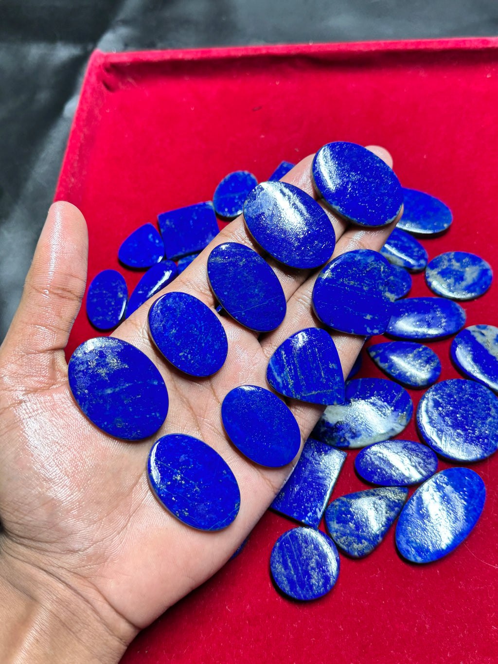 Smooth blue lapis lazuli cabochon gemstones, assorted oval cabochons in hand