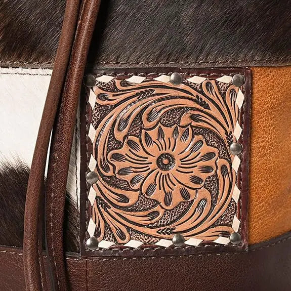 Western-style bucket bag in brown and white hair-on hide leather featuring a floral-tooled leather square patch.