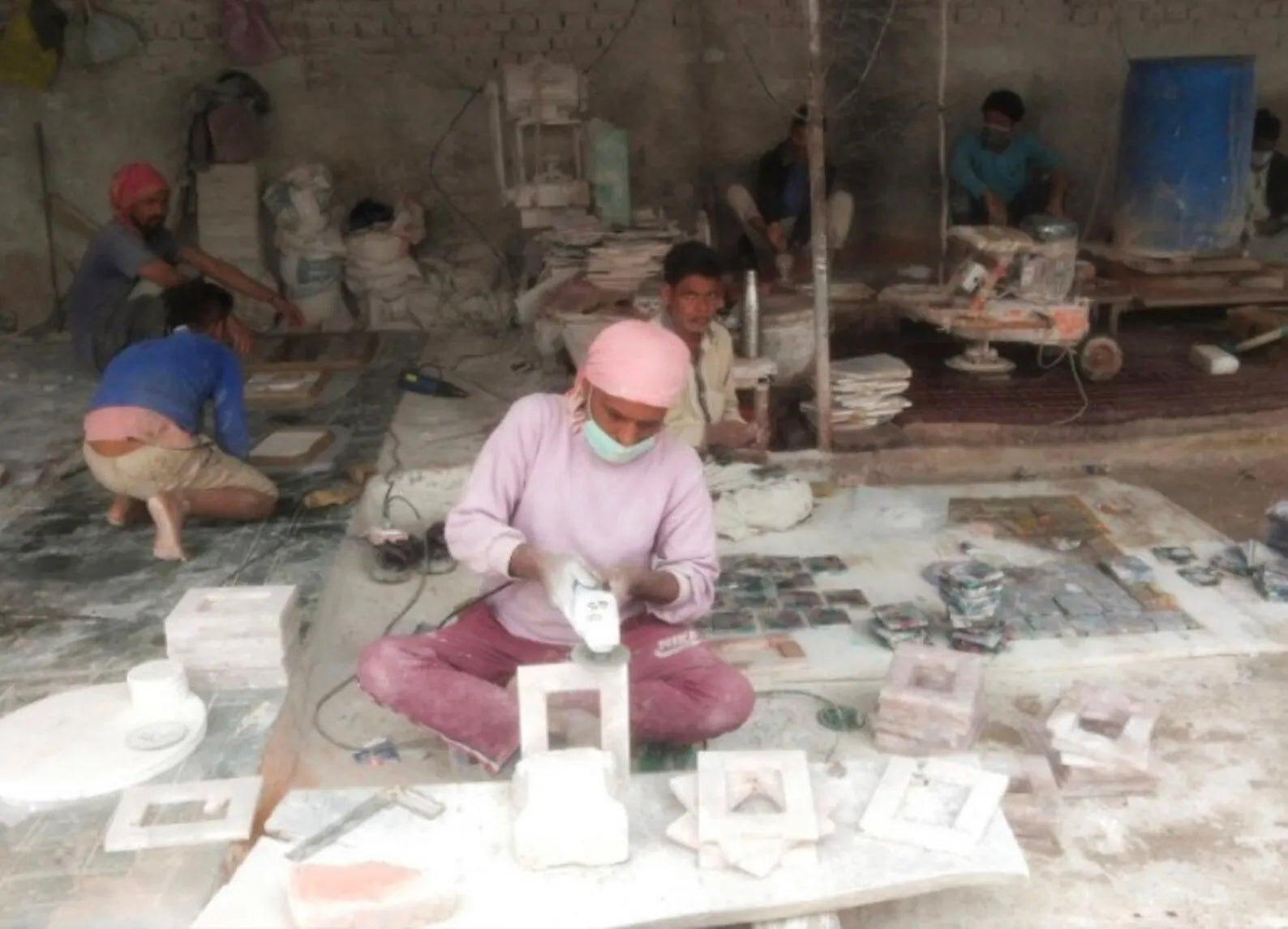 Worker shaping materials at a crafting table with tools and stone pieces