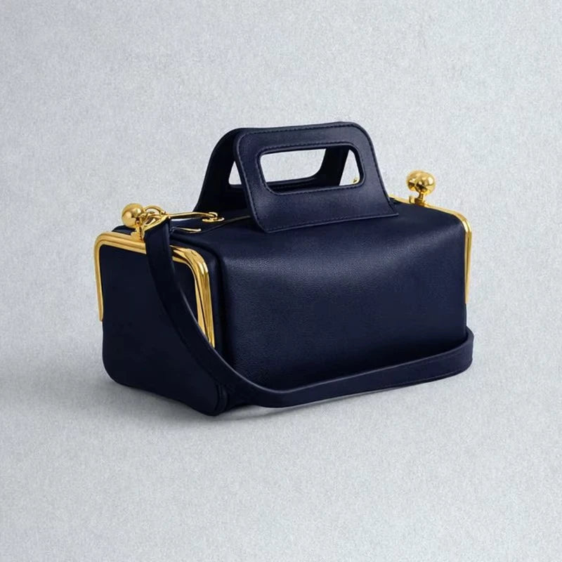 Navy blue retro PU leather pillow bag with gold clasp hardware, top handle, and detachable shoulder strap.