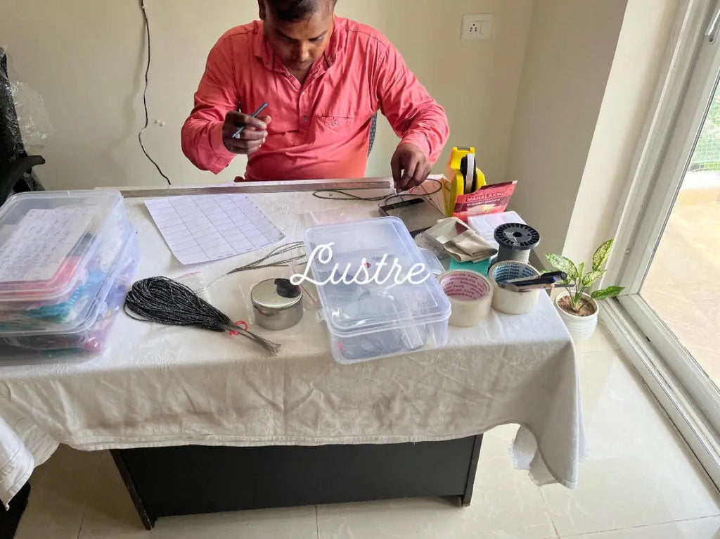 Person working at a table with tools and containers for gemstone bead strands