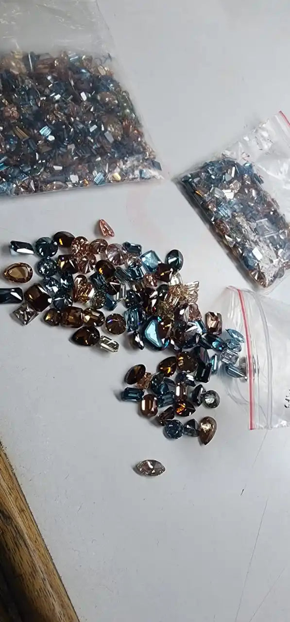 Loose faceted lab-grown diamond stones, scattered blue and brown mix on clear sheet