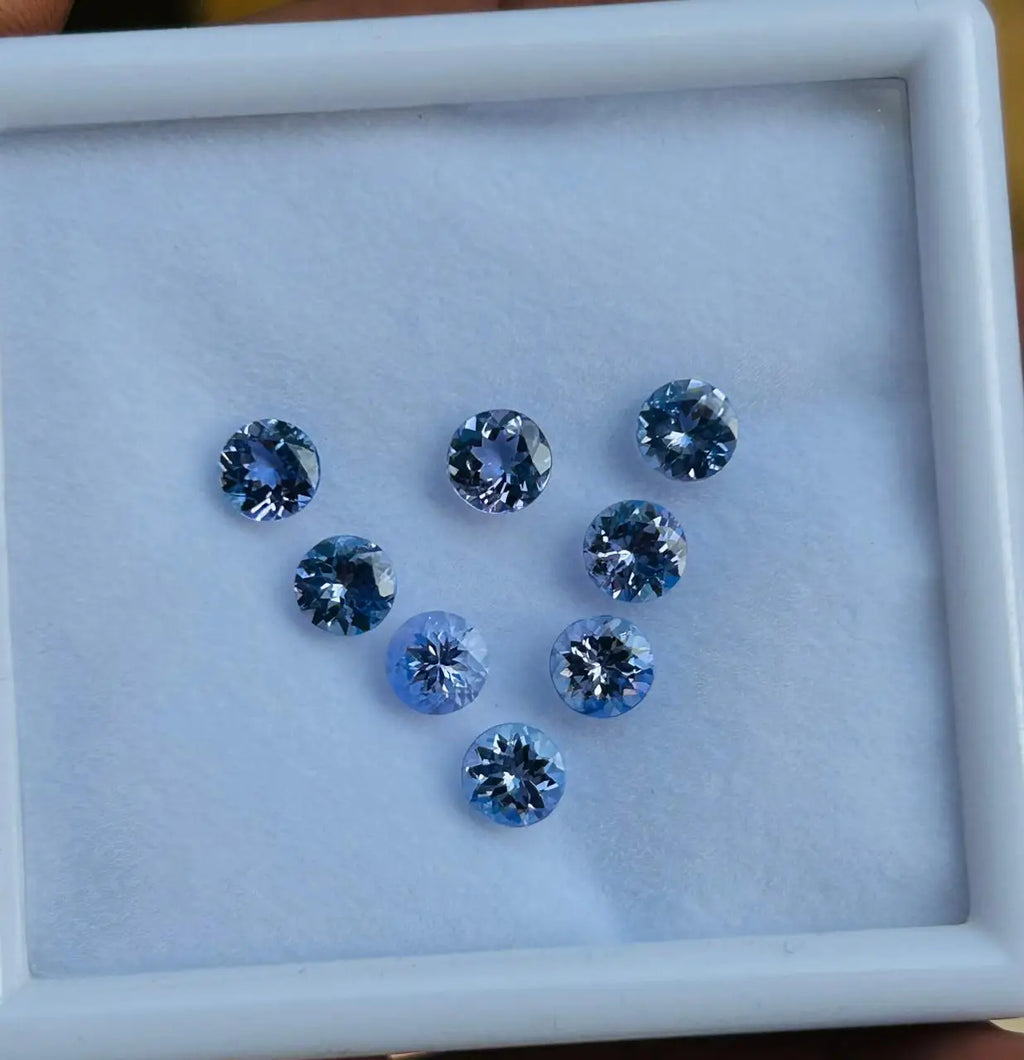 Set of small sky-blue round faceted gemstones in a tray