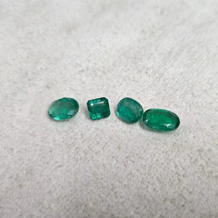 Loose green emerald-cut gemstone mix, four stones in mixed shapes on felt