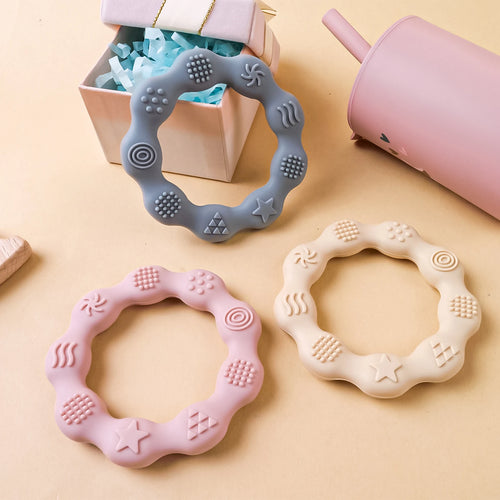 Grey, pink, and cream silicone baby teething rings for infant teething relief.