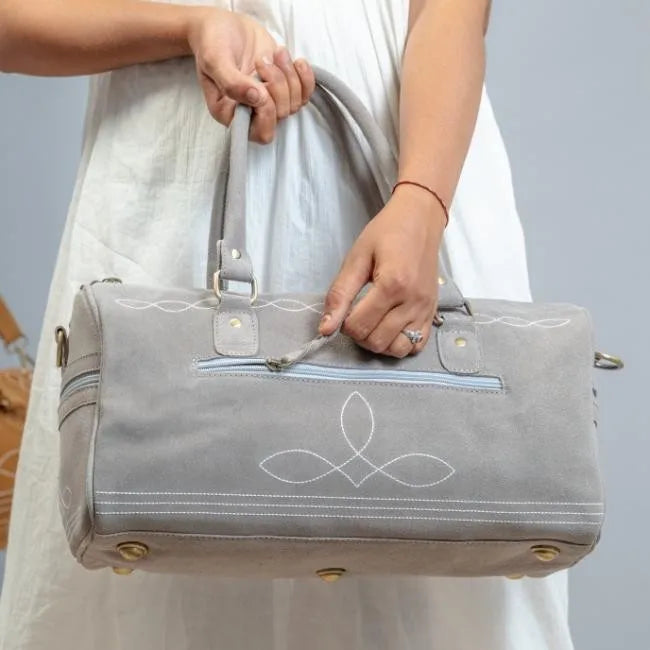 Handmade grey leather weekend duffel bag with white boot stitch detail, brass hardware, and zip closure.