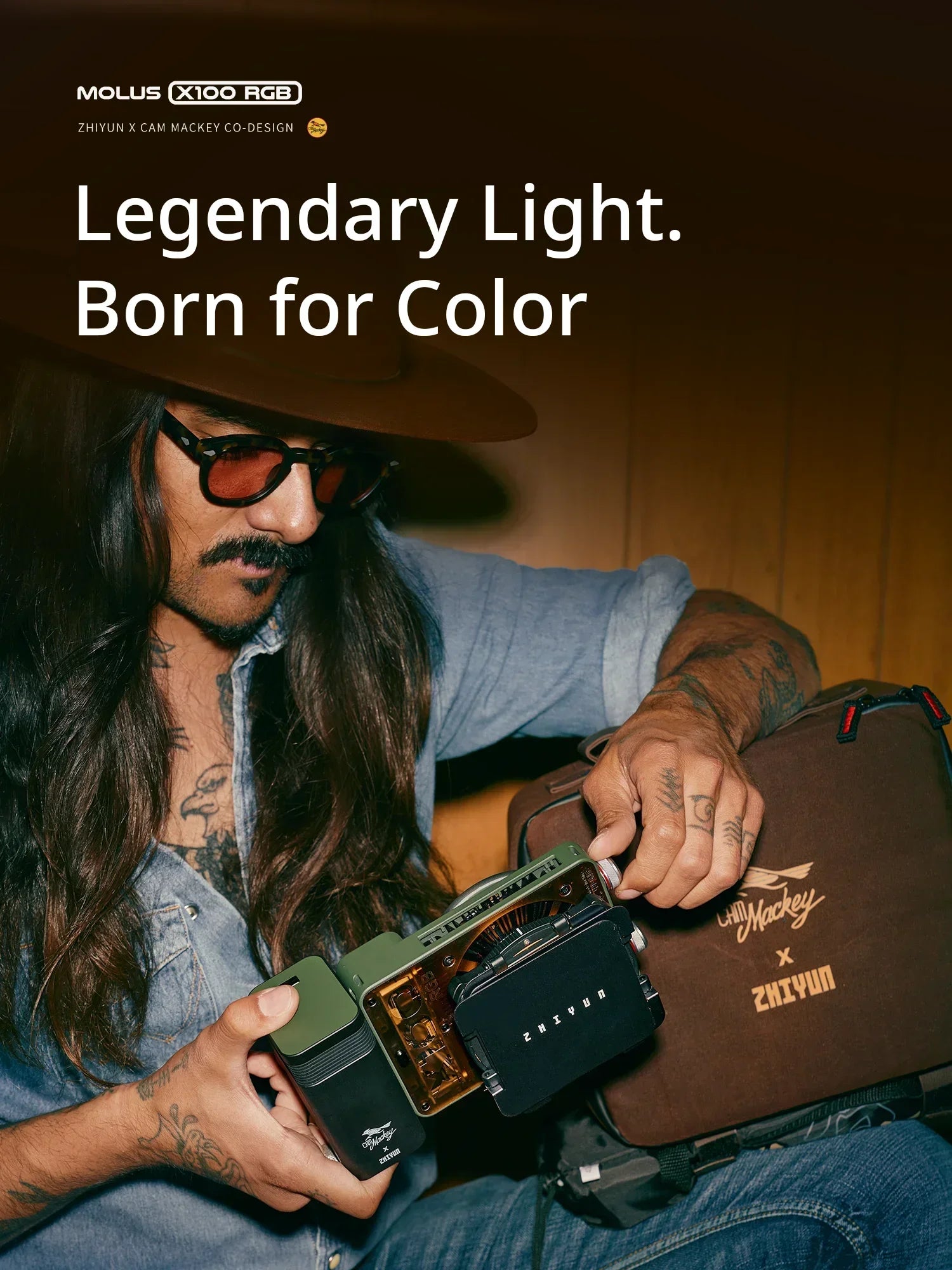 Compact, olive-green handheld Molus X100 RGB LED light for photography and videography, held by a person in a studio.
