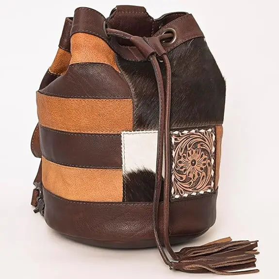 Brown patchwork leather bucket bag with fur accents, floral embossed leather detail, drawstring closure, and tassel.