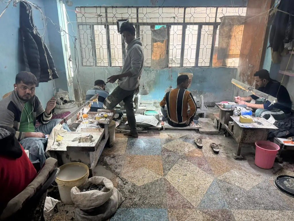 Seated workshop workers with crafting tools on tables and supplies