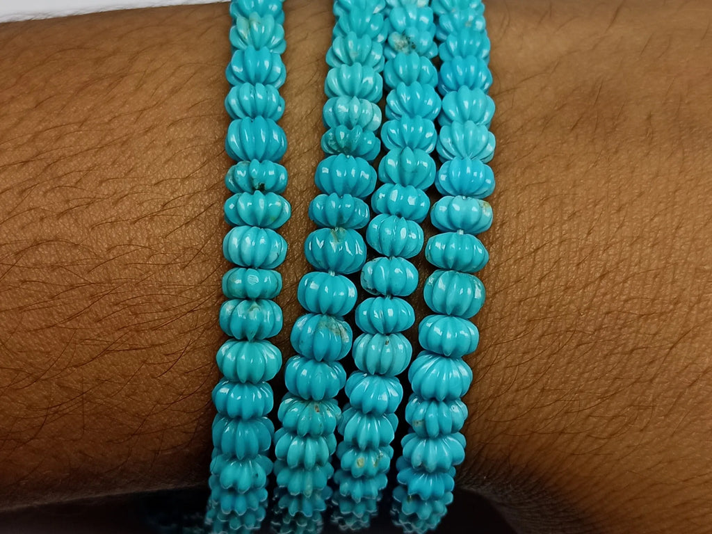 Blue turquoise carved pumpkin-shaped bead strands on wrist, close-up ribbed bead texture