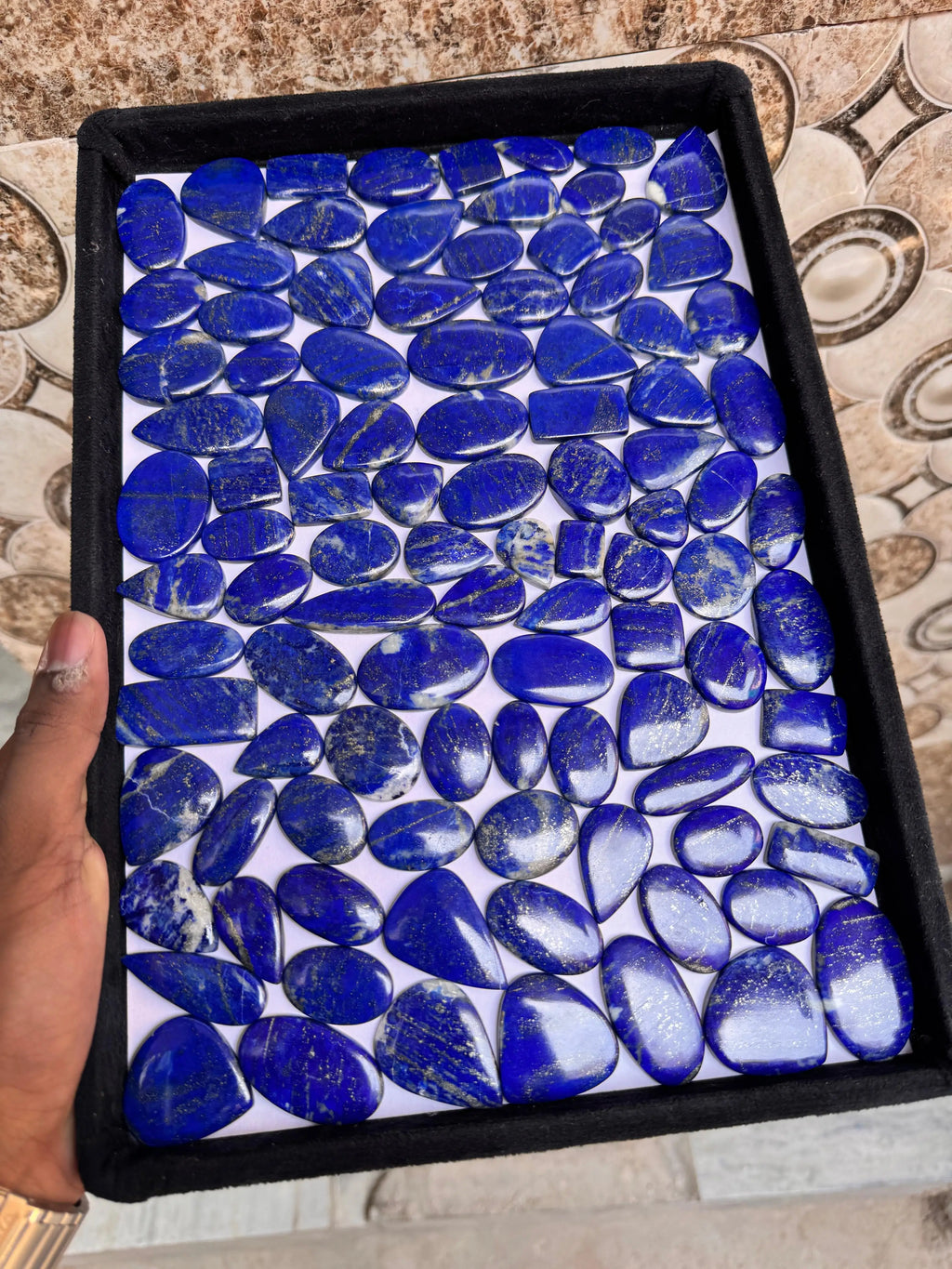 Lapis lazuli cabochon gemstone assortment in a square tray, blue smooth stones