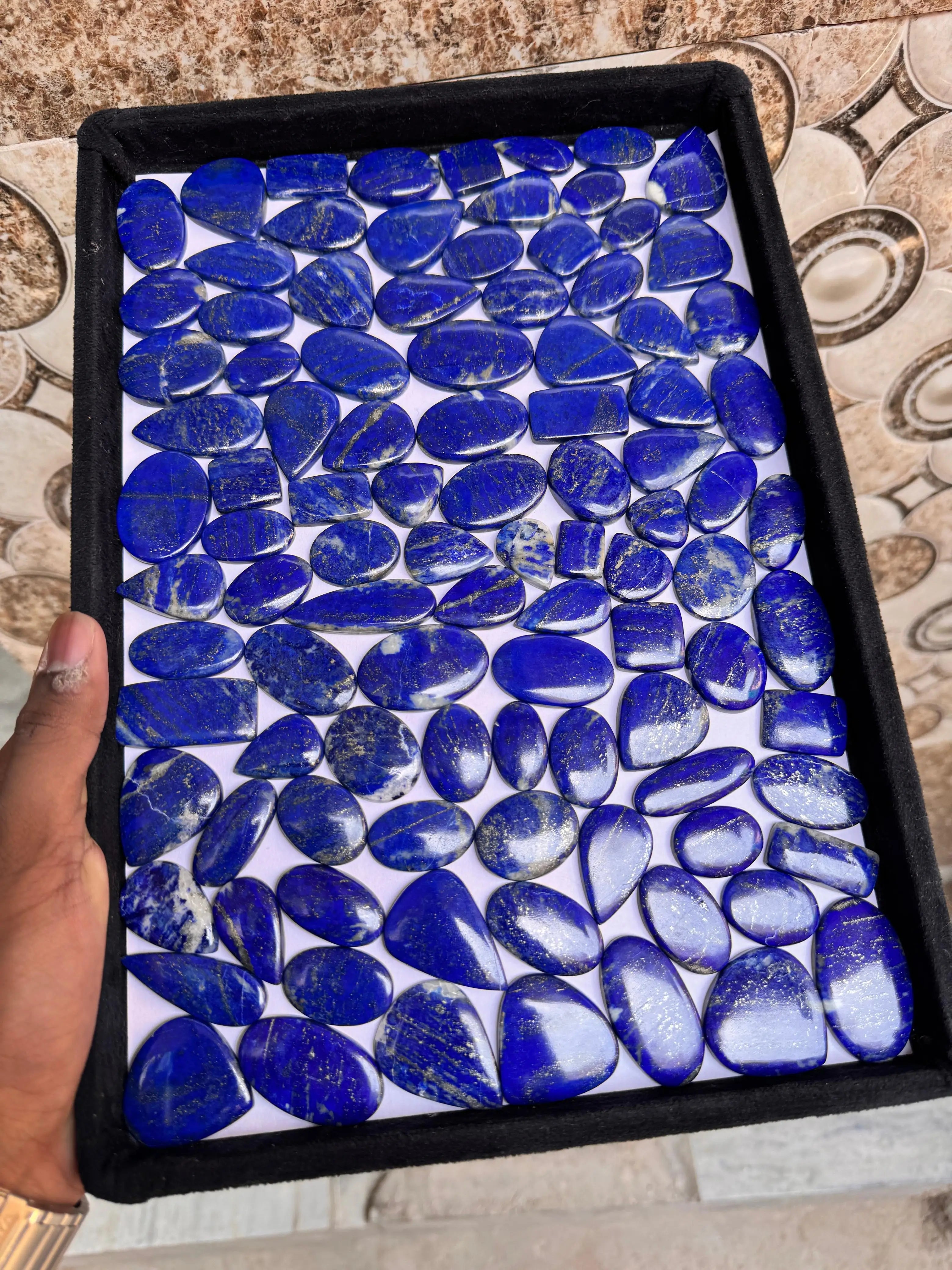 Lapis lazuli cabochon gemstone assortment in a square tray, blue smooth stones