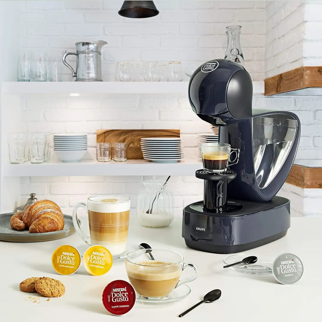 Dark grey Krups Nescafé Dolce Gusto pod coffee machine brewing espresso on a modern kitchen counter.