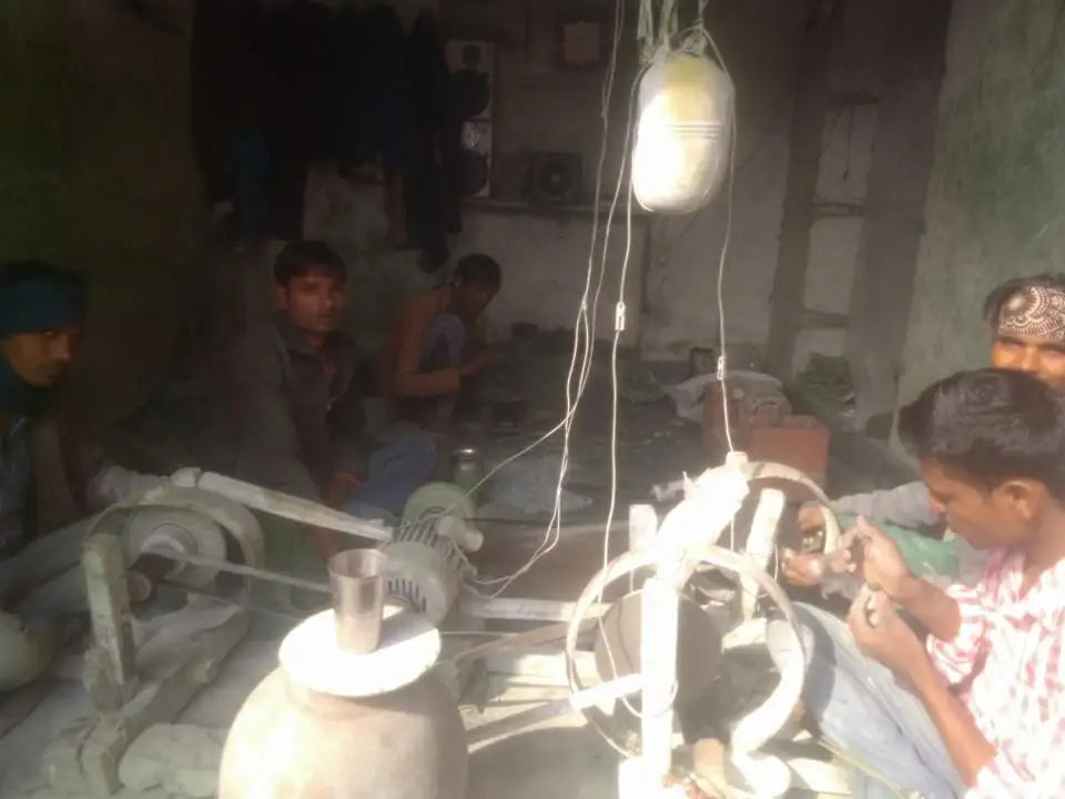 Dim gemstone workshop with workers near lamps and polishing equipment