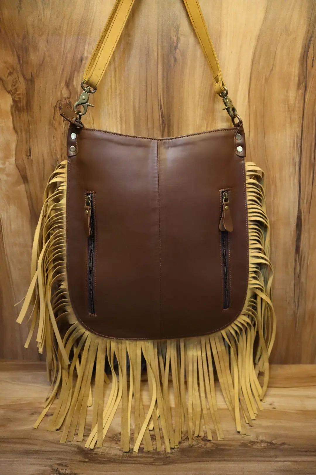 Brown genuine leather crossbody handbag with long yellow fringe, zipper pockets, and detachable shoulder strap.