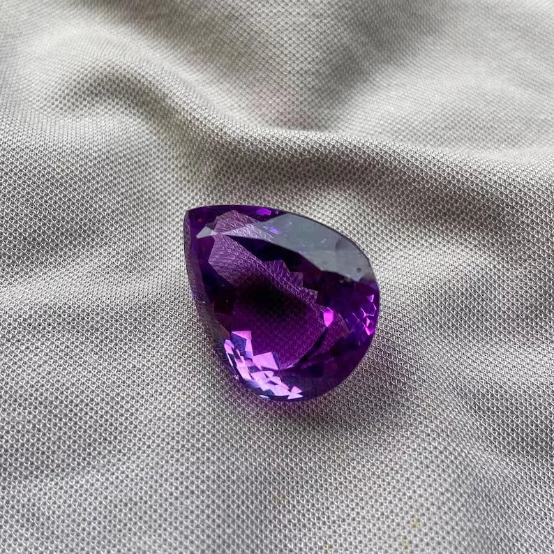 Amethyst pear cut gemstone showing dark purple interior facets and vivid sparkle