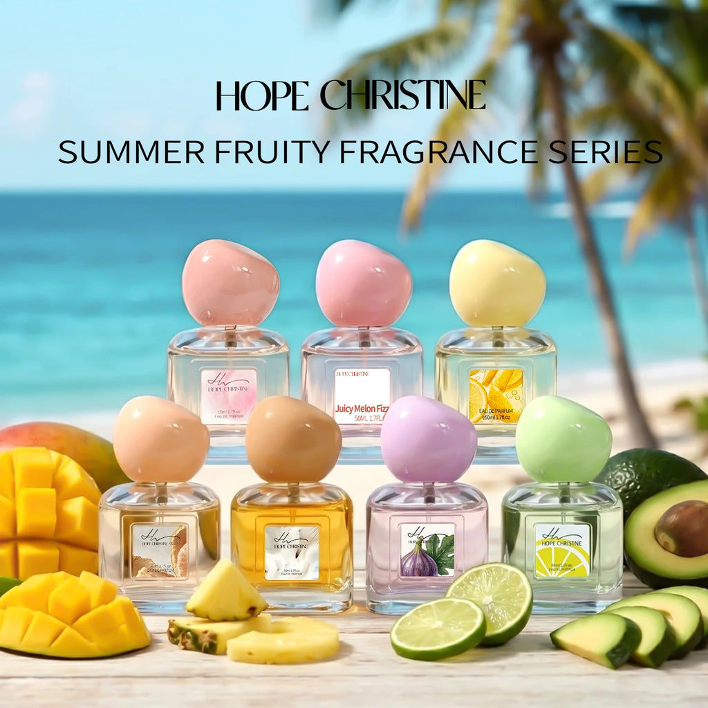 Seven glass perfume bottles with pastel, pebble-shaped caps arranged on a beach surface with tropical fruit.