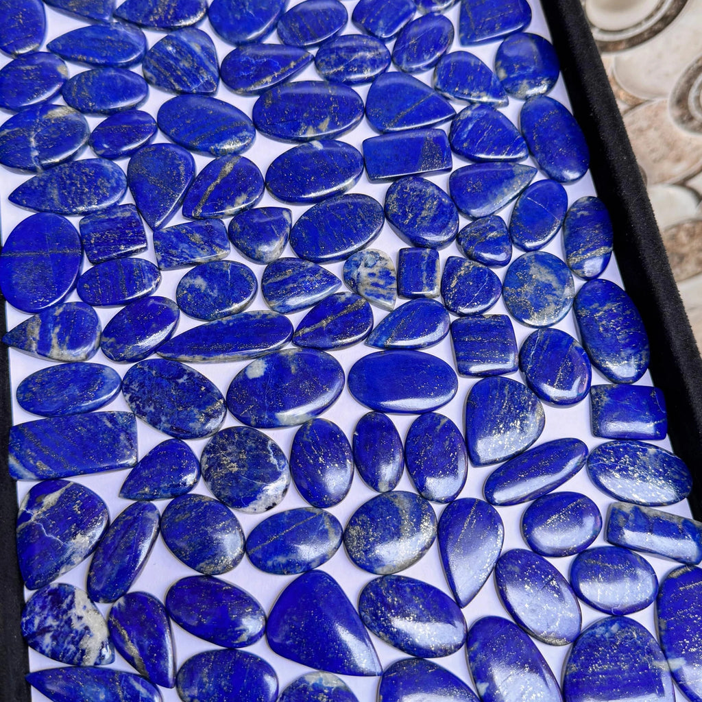 Lapis lazuli gemstone cabochons, smooth blue oval and round stones in close-up