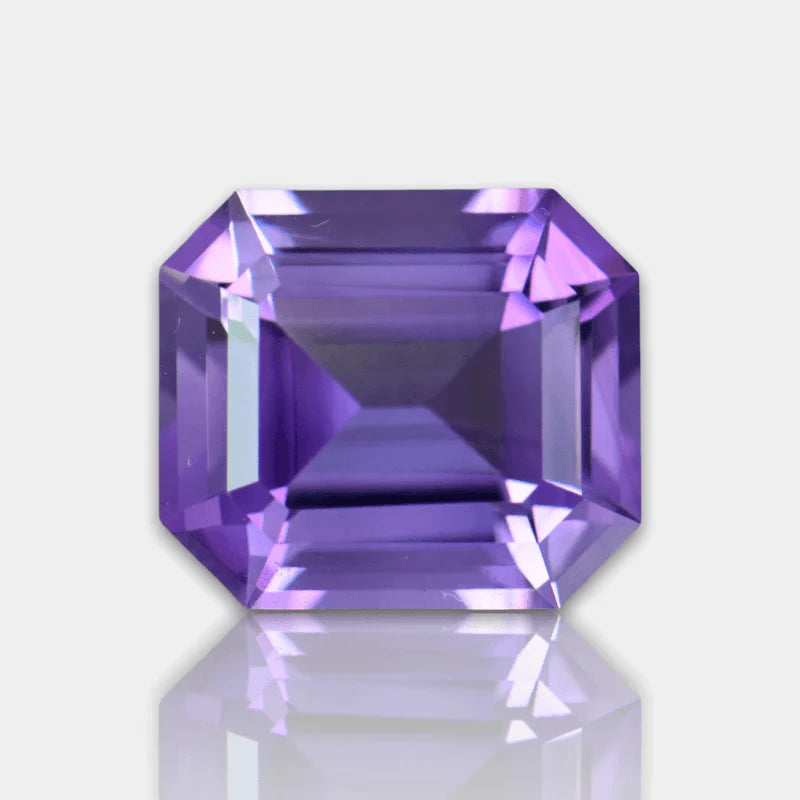 Emerald-cut purple amethyst gemstone close-up, reflective facets on white