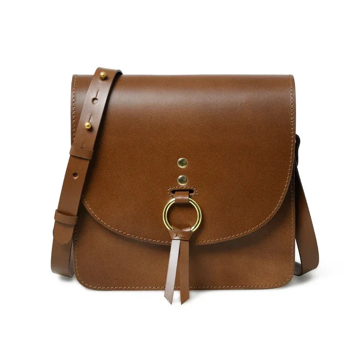 Luxury brown leather crossbody designer handbag with gold ring hardware, adjustable strap, and minimalist saddle style.