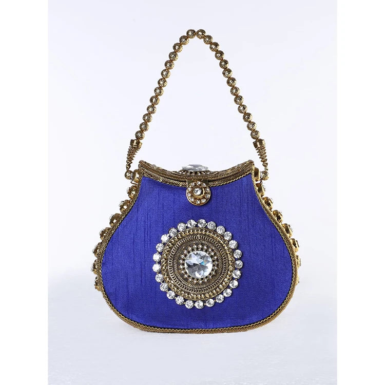 Royal blue silk designer handbag with gold metal beaded trim, crystal center embellishment, and kiss lock closure.