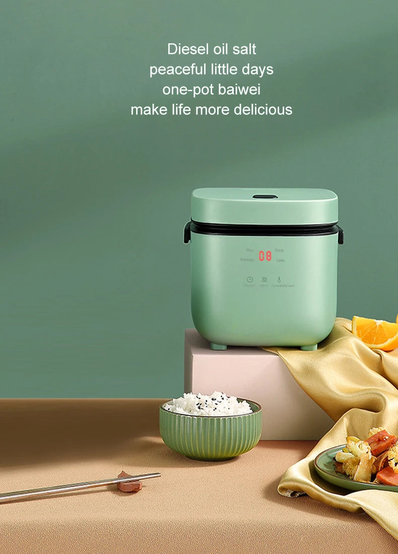 Mini electric rice cooker with green body on table beside a small rice bowl.