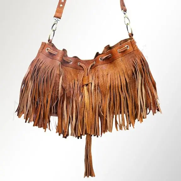 Tan leather boho bucket bag featuring long fringe, tassel detail, and adjustable shoulder strap.