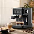 Matte black espresso machine with steam wand, touch controls, and two glass cups on a kitchen counter.