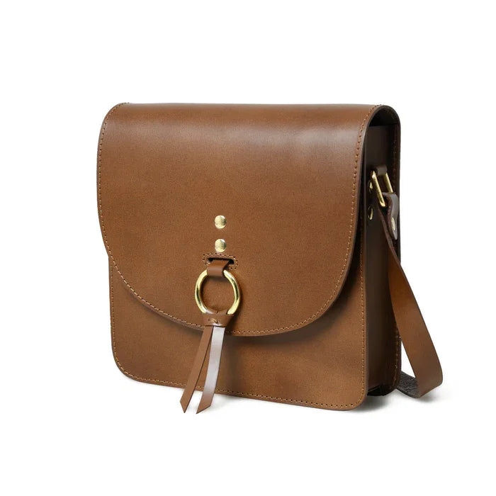 Brown leather designer crossbody bag with gold ring clasp and tassel detail. Stylish unisex everyday handbag.