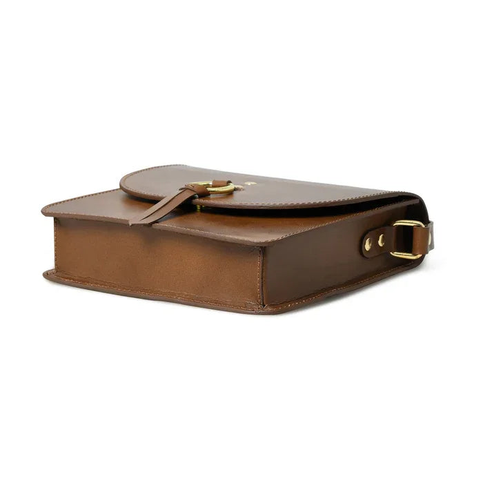 Brown leather designer crossbody bag with gold-tone hardware, fold-over strap closure, and sleek, minimalist style.