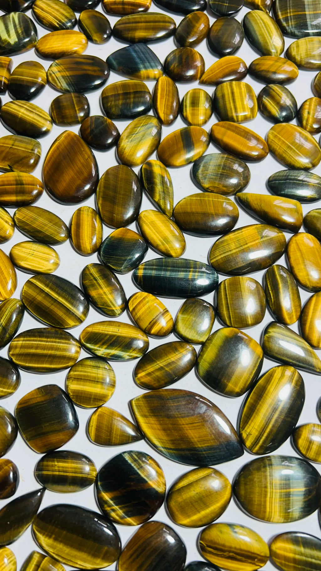 Assorted yellow-gold striped cabochon gemstones, glossy oval and pear shapes