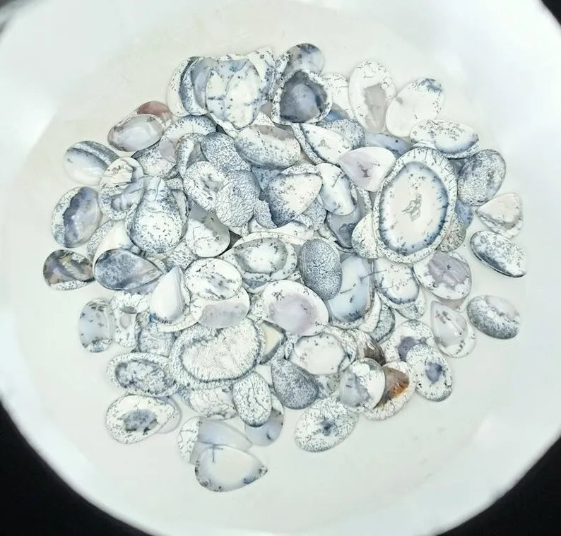 Top view of oval dendrite opal cabochon stones, white with black speckles
