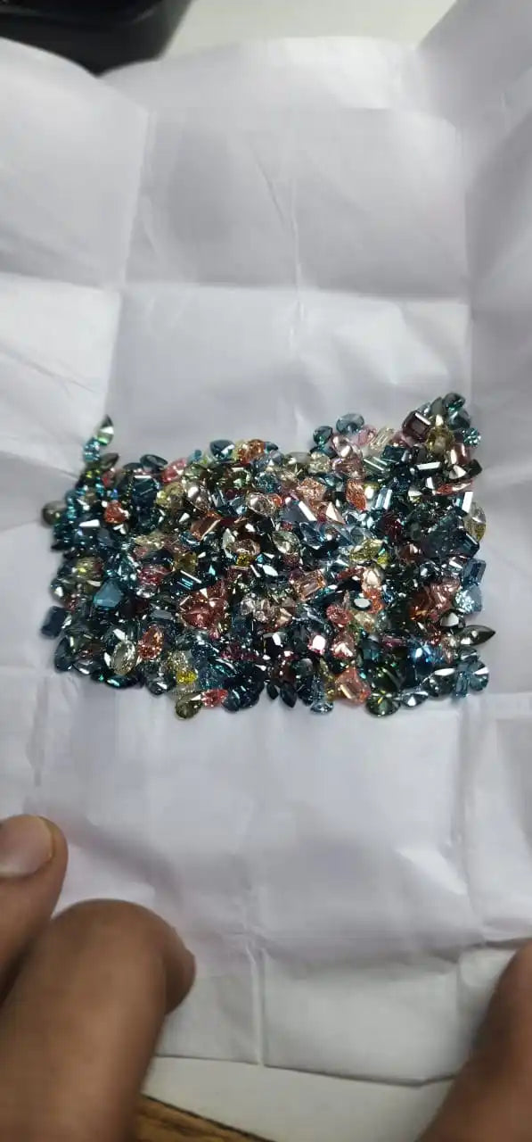 Blue-toned loose lab-grown diamond stones pile on white tissue, faceted mix