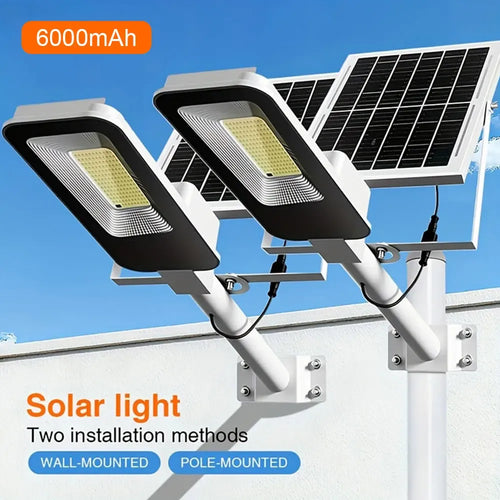 Two white and black LED solar street lamps mounted on a wall and pole, each with an attached solar panel.