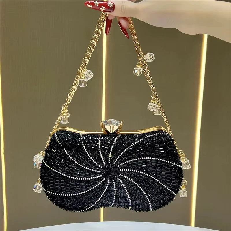 Black crystal-embellished evening clutch with gold chain strap, bead accents, and decorative gem clasp. Designer handbag.
