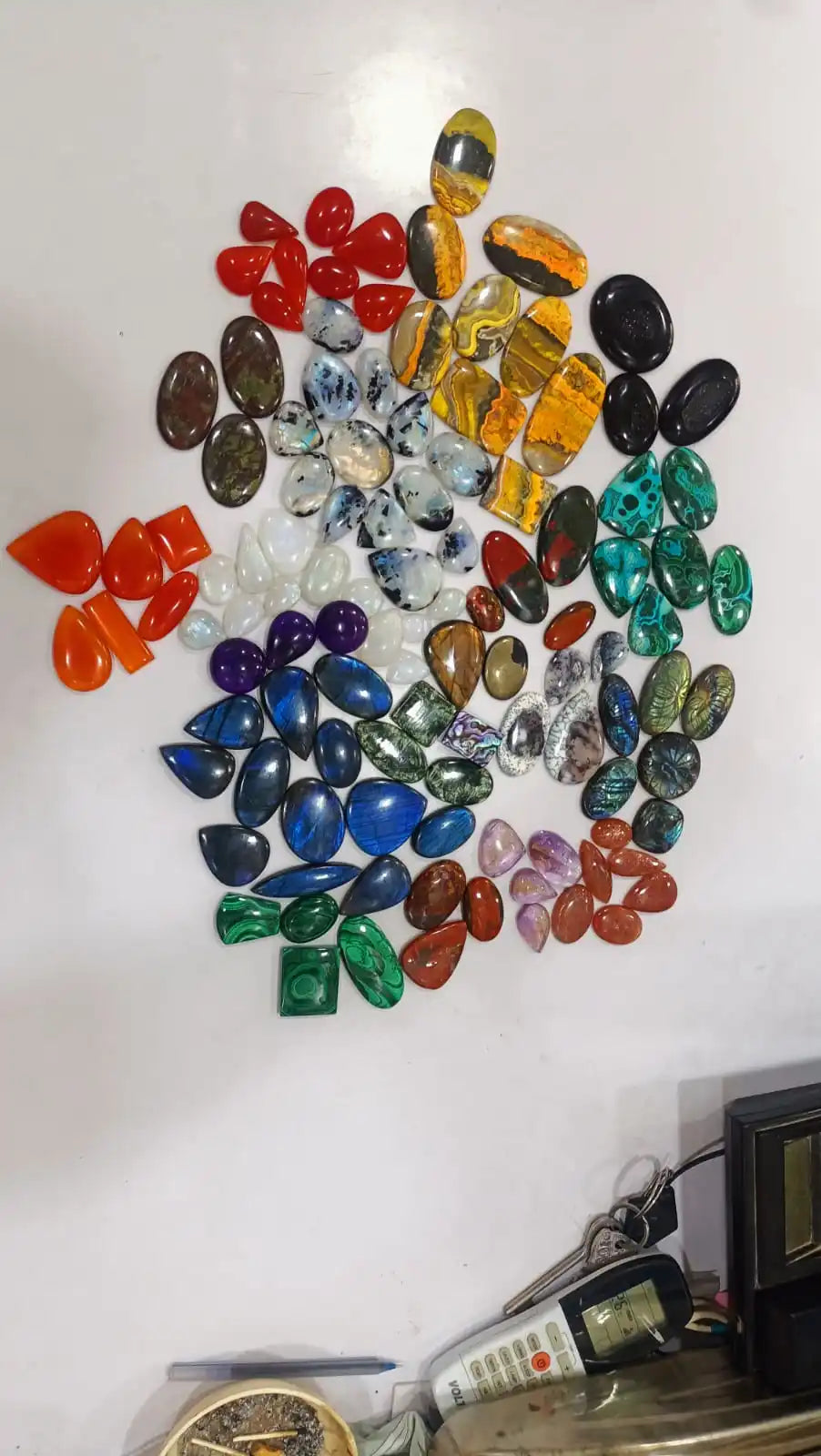 Mixed-shape cabochon gemstone pile with red, gold, green, black, and blue stones