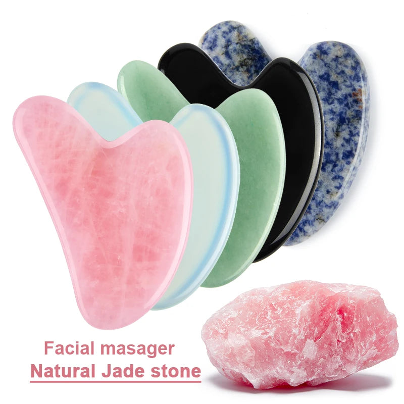 Five heart-shaped gua sha massage tools in pink, blue, green, black, and speckled blue, plus a raw pink stone.