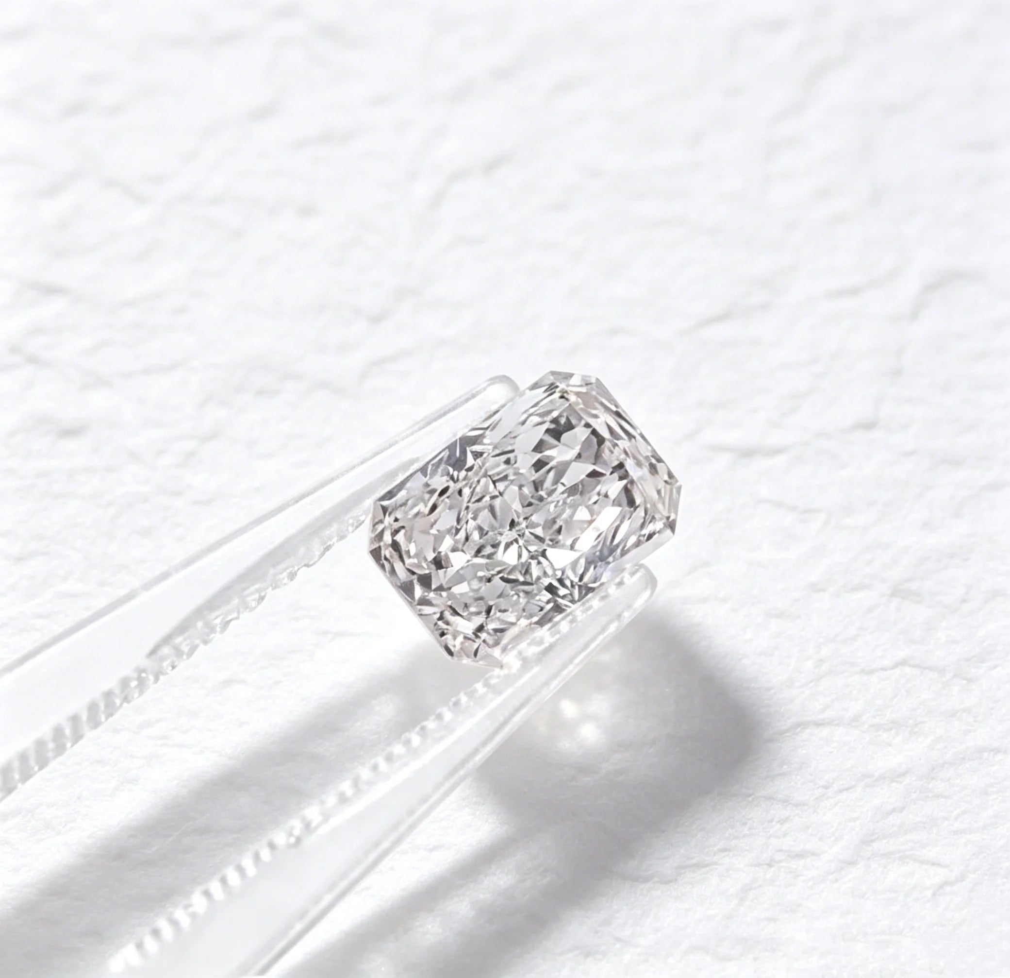Lab-grown radiant-cut diamond lying on a metal band