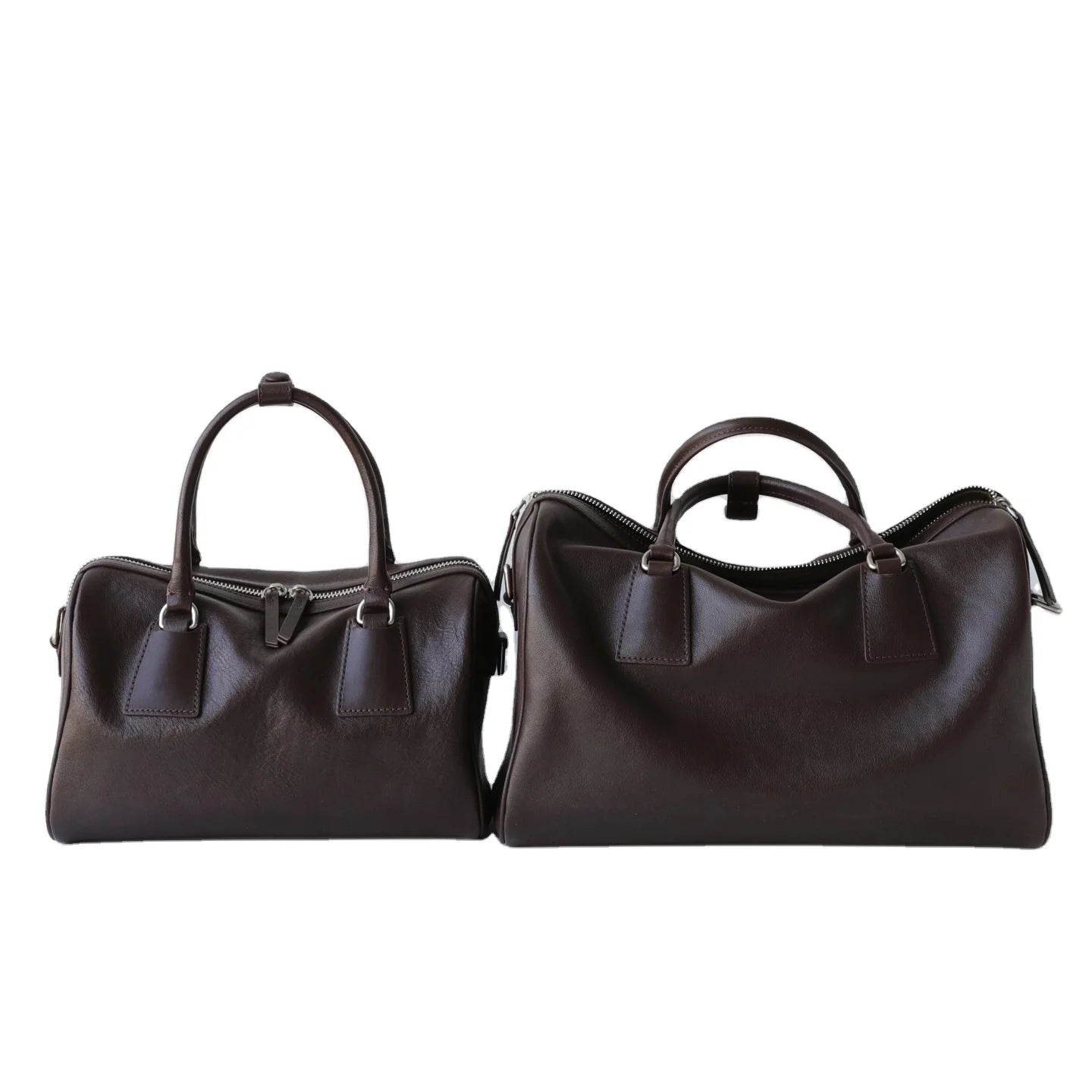 Two minimalist dark brown vegetable-tanned leather designer Boston bags with double zip closures and sturdy handles.