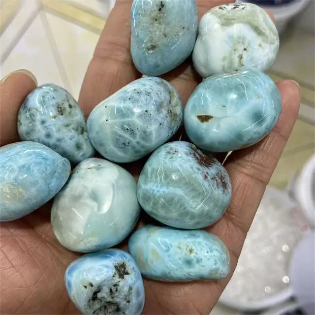 Hand of sky blue tumbled larimar stones, glossy surface with natural inclusions