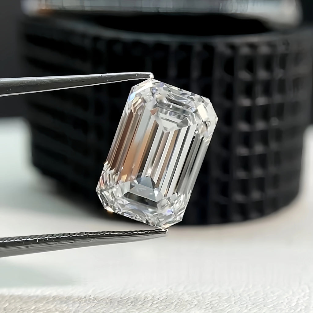 Emerald-cut lab-grown diamond loose stone held by metal tweezers, angled side view.