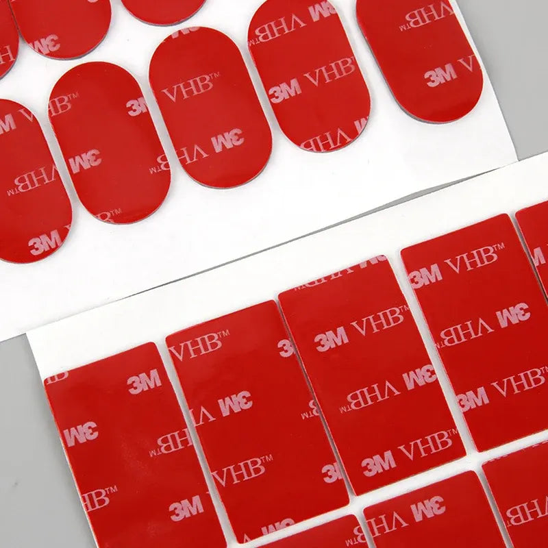 Red die-cut double-sided acrylic foam tape pads on release sheet, grid of squares