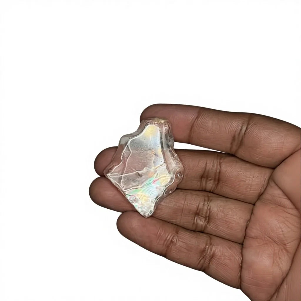Hand-held iridescent rough gemstone, polished topaz-like with rainbow sheen